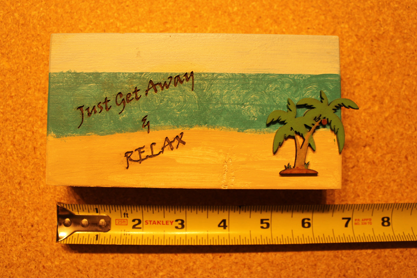 Sign that reads "Just Get Away & Relax" with a beach scenery and palm tree
